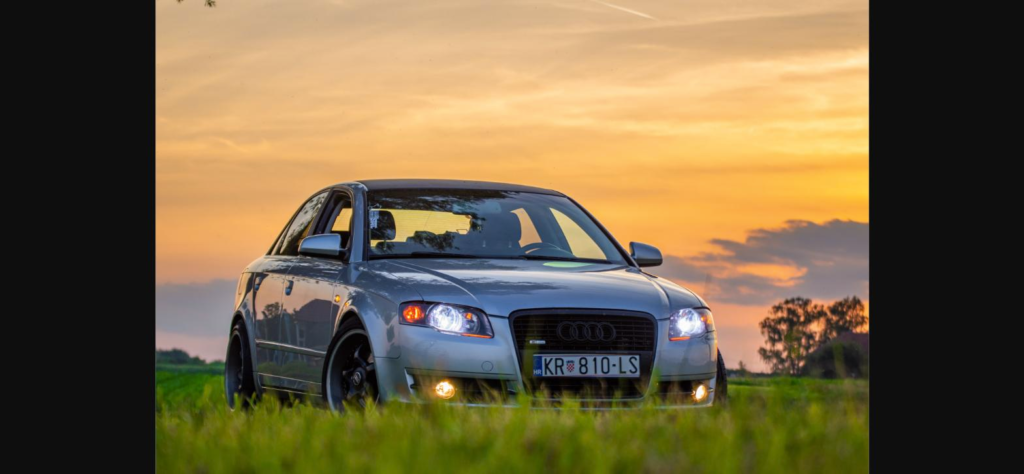 Luxury car parked in a field at sunset